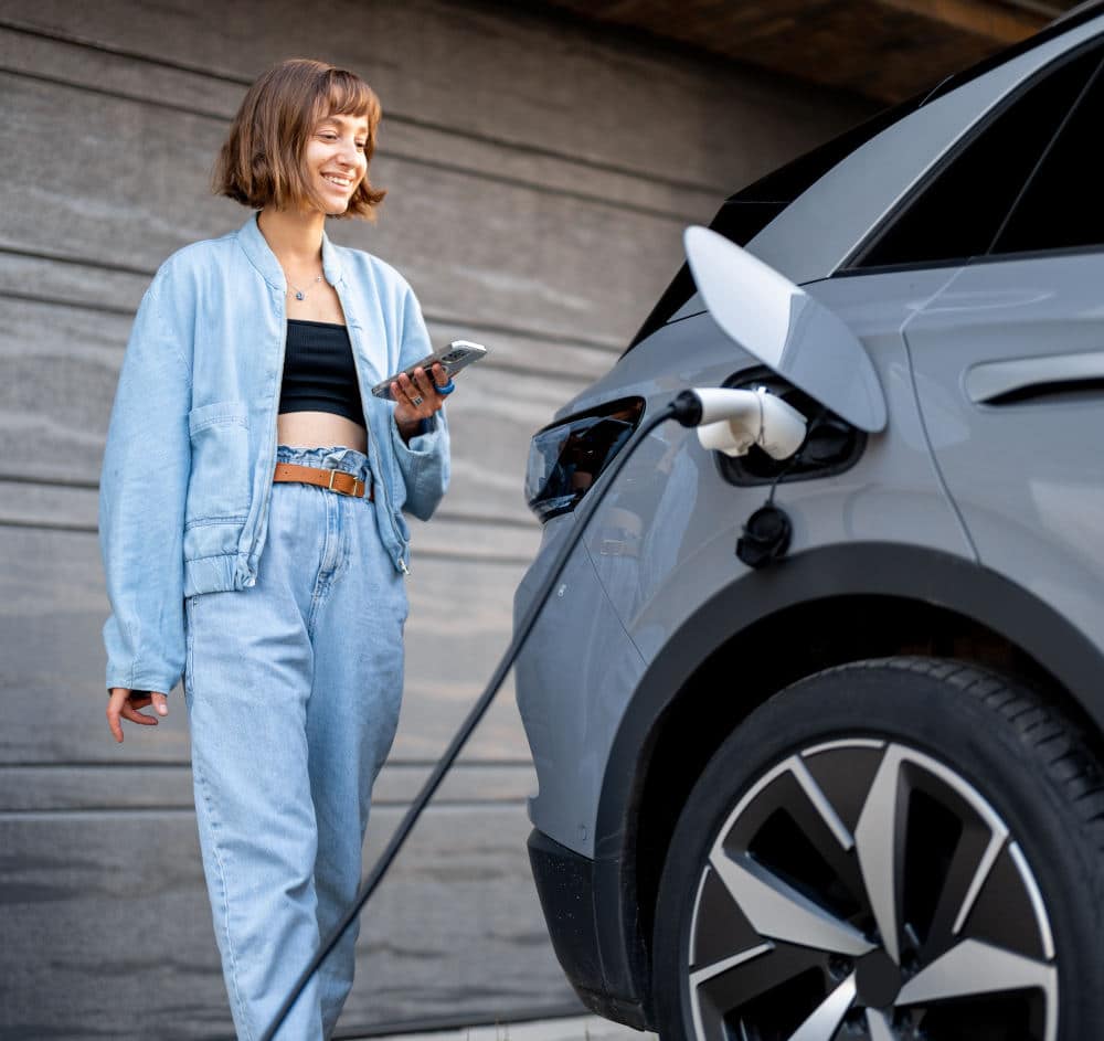 Woman charges her electric car near a house